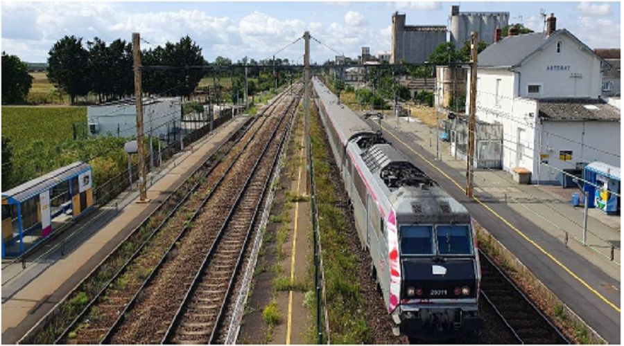 Train en gare à quais et gare en arrière-plan